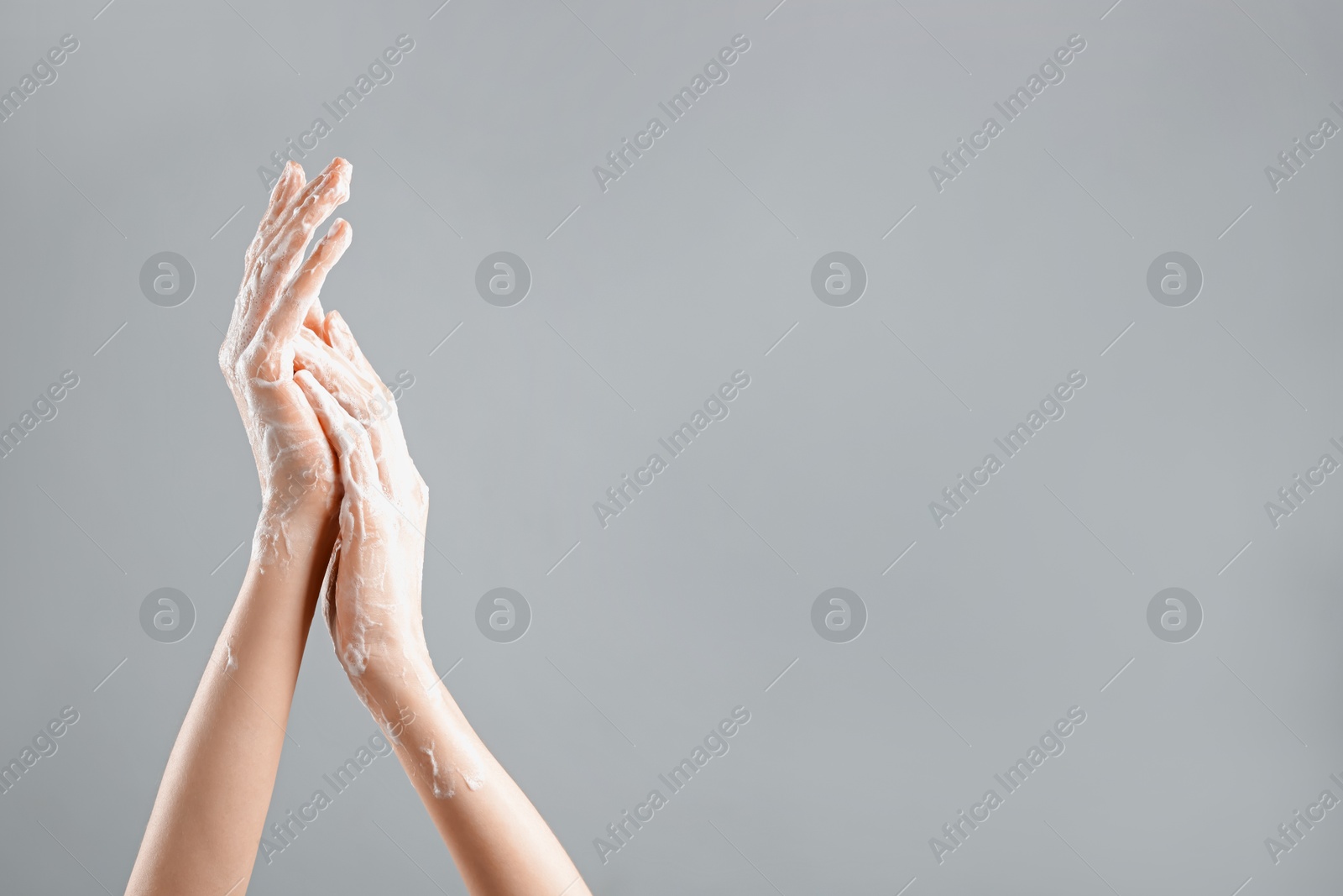 Woman washing hands with soap foam on light grey background, closeup. Space for text Photo of Woman washing hands with soap foam on light grey background, closeup. Space for text