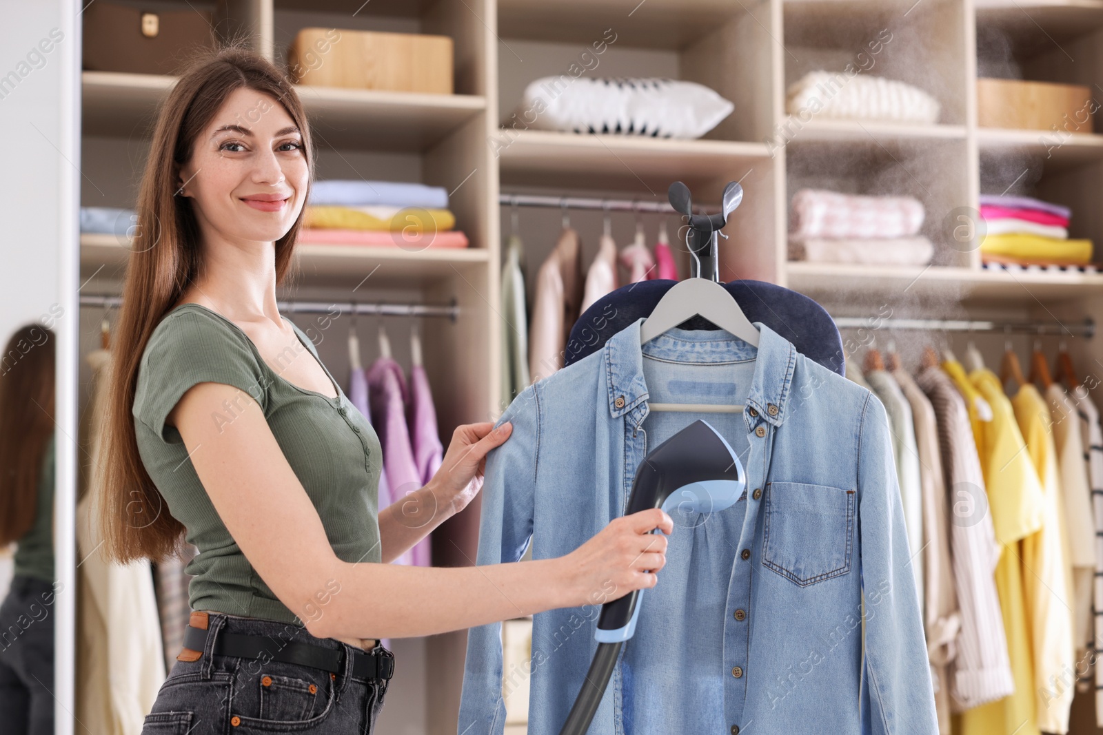 Photo of Woman steaming shirt on stand at home