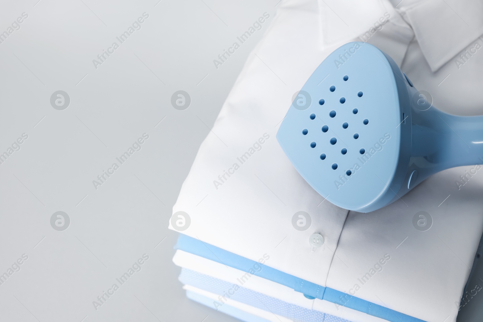 Upright steamer and stack of folded shirts on grey background, above view. Space for text Photo of Upright steamer and stack of folded shirts on grey background, above view. Space for text