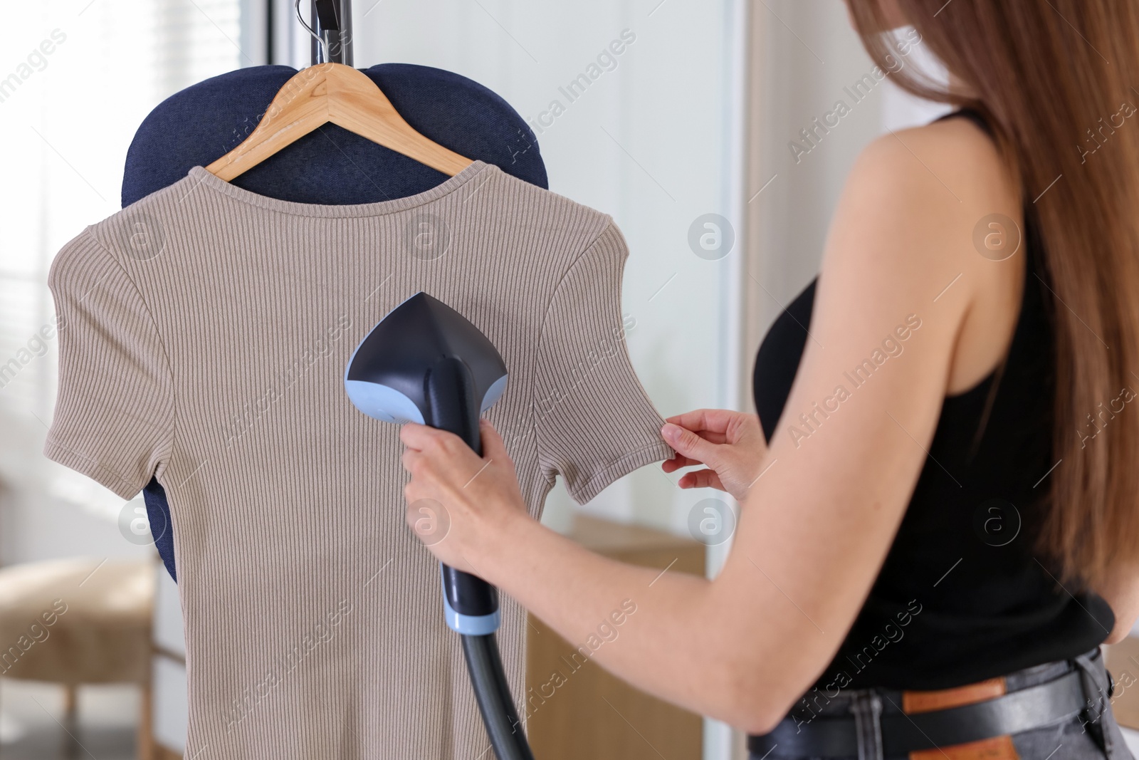Photo of Woman steaming dress on stand at home, closeup