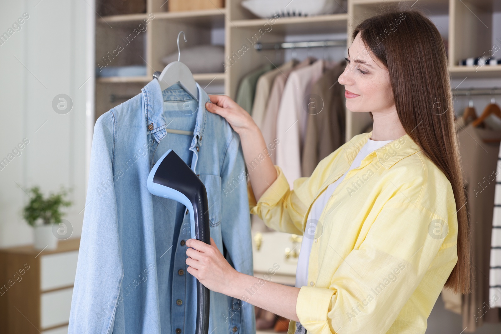 Woman steaming shirt on hanger at home Photo of Woman steaming shirt on hanger at home