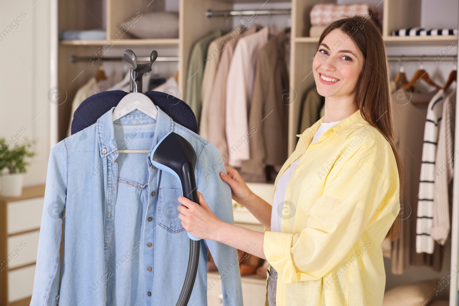 Smiling woman steaming shirt on stand at home Photo of Smiling woman steaming shirt on stand at home