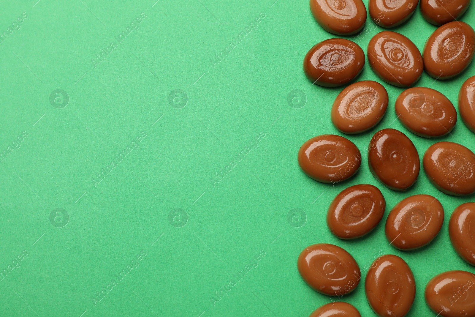 Many tasty caramel candies on green background, flat lay. Space for text Photo of Many tasty caramel candies on green background, flat lay. Space for text