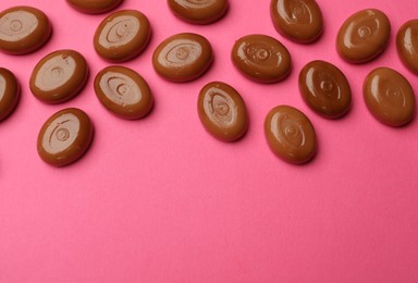 Photo of Many tasty caramel candies on pink background, flat lay. Space for text