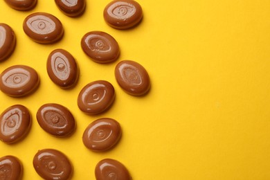 Photo of Many tasty caramel candies on yellow background, flat lay. Space for text