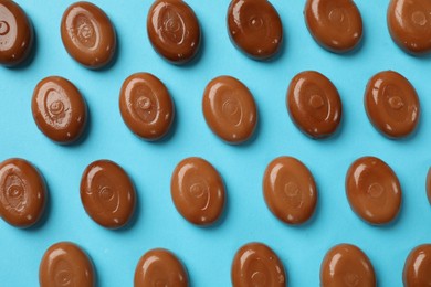 Photo of Many tasty caramel candies on light blue background, flat lay