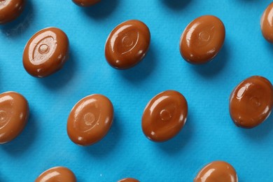 Photo of Many tasty caramel candies on light blue background, flat lay