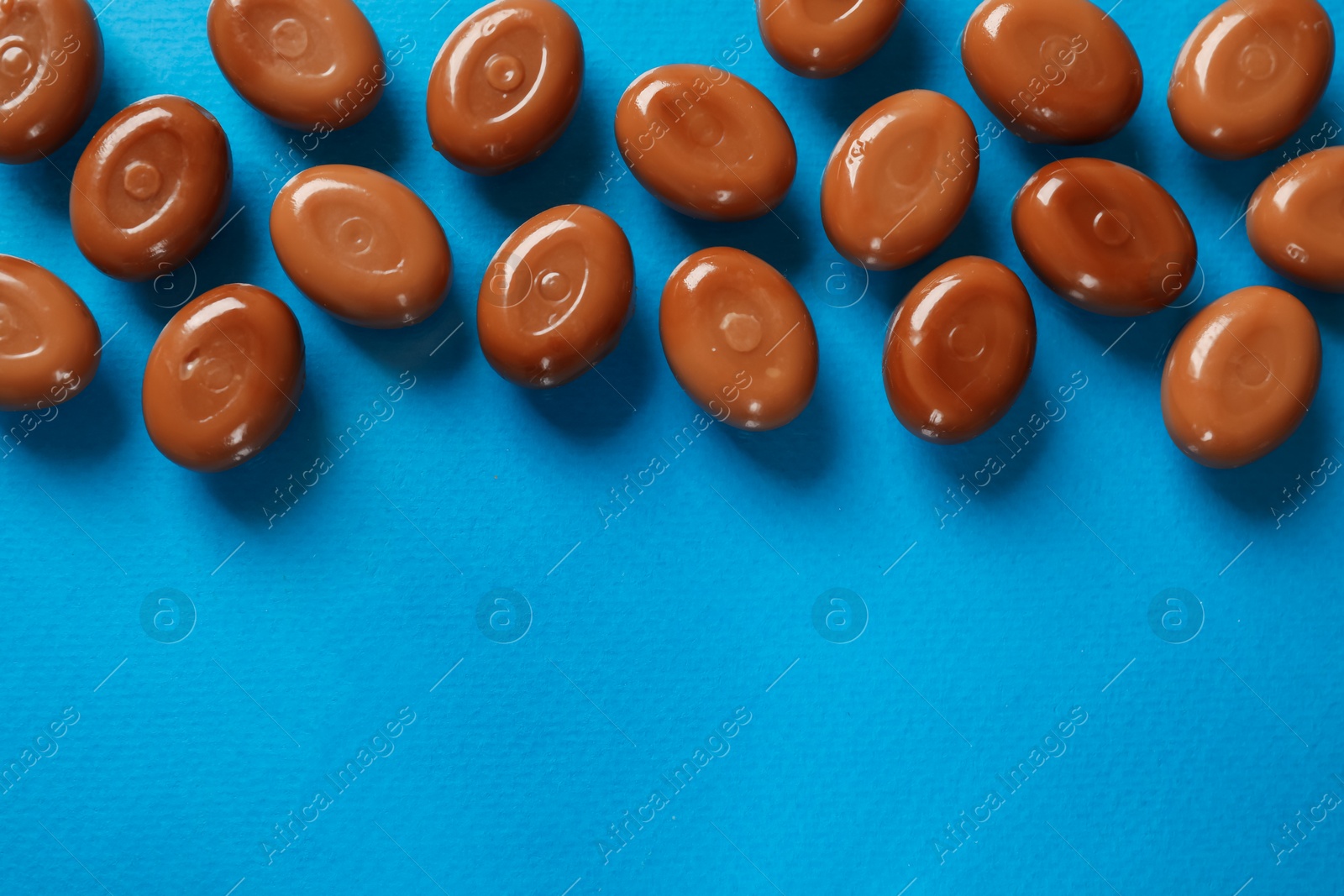 Many tasty caramel candies on light blue background, flat lay. Space for text Photo of Many tasty caramel candies on light blue background, flat lay. Space for text