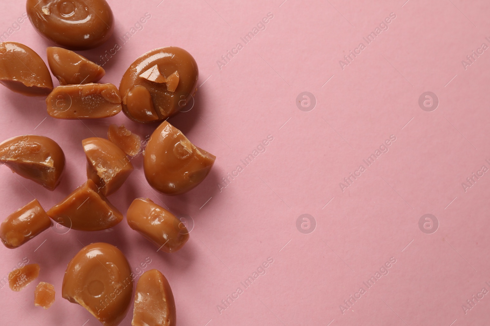 Many tasty caramel candies on light pink background, flat lay. Space for text Photo of Many tasty caramel candies on light pink background, flat lay. Space for text