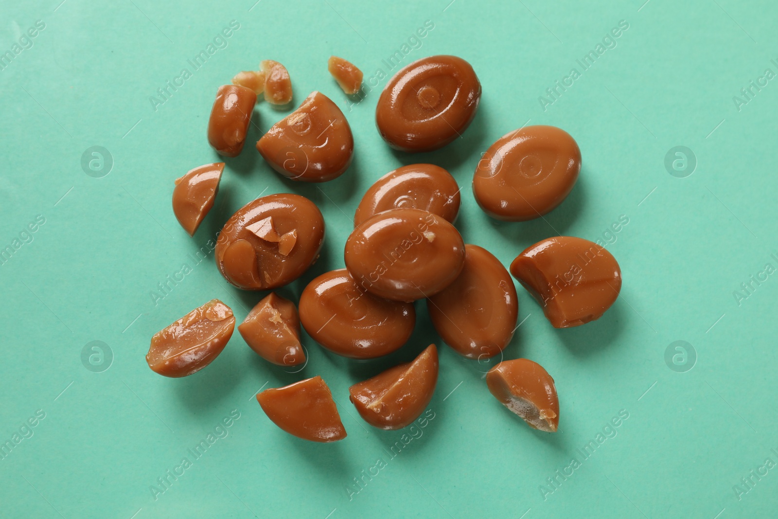 Many tasty caramel candies on turquoise background, flat lay Photo of Many tasty caramel candies on turquoise background, flat lay