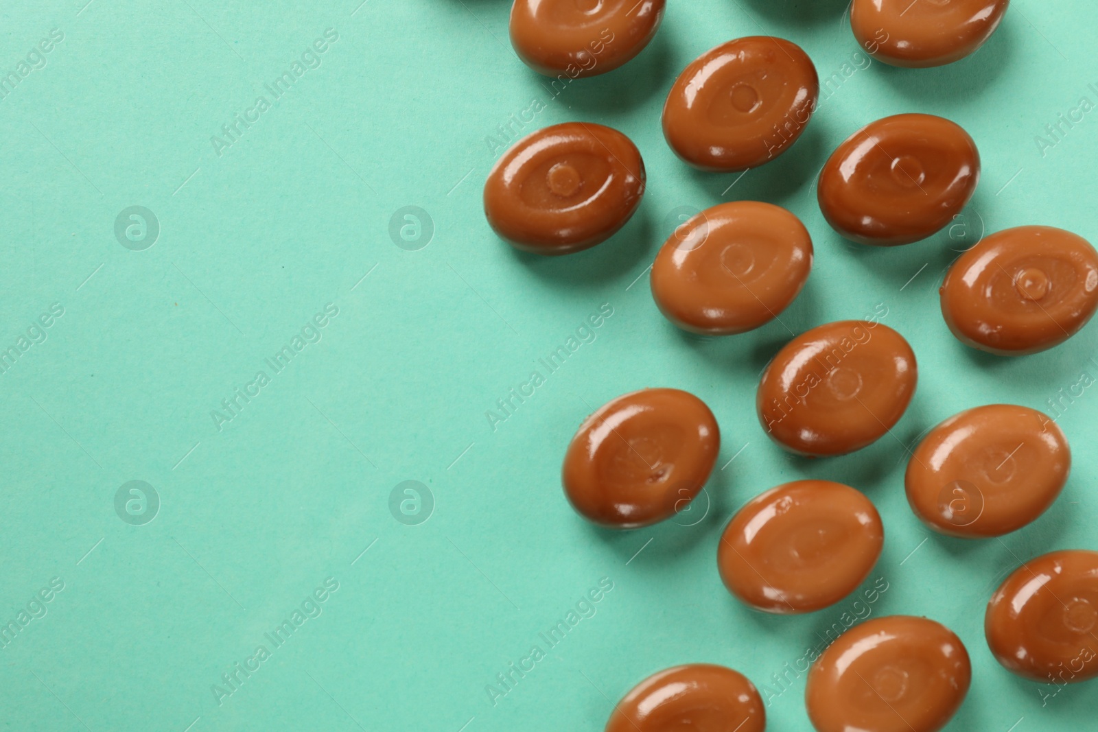 Many tasty caramel candies on turquoise background, flat lay. Space for text Photo of Many tasty caramel candies on turquoise background, flat lay. Space for text