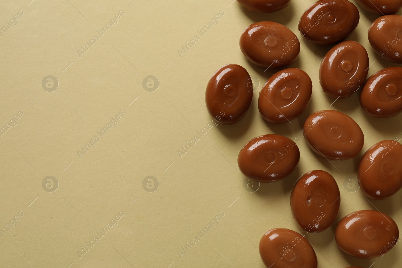 Many tasty caramel candies on beige background, flat lay. Space for text Photo of Many tasty caramel candies on beige background, flat lay. Space for text