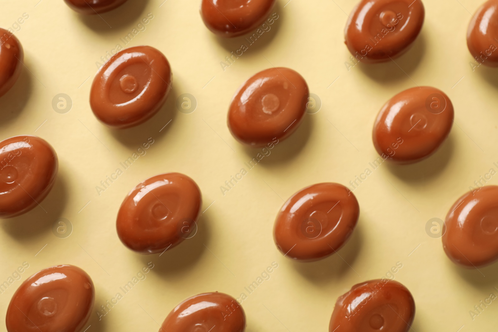Many tasty caramel candies on beige background, flat lay Photo of Many tasty caramel candies on beige background, flat lay