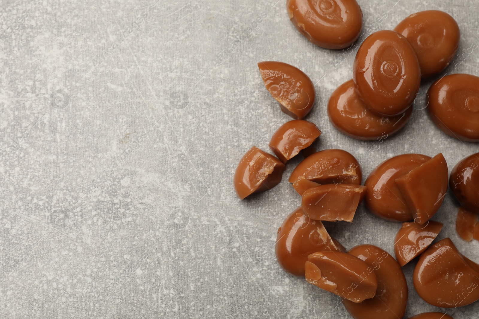 Many tasty caramel candies on grey table, flat lay. Space for text Photo of Many tasty caramel candies on grey table, flat lay. Space for text