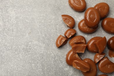 Photo of Many tasty caramel candies on grey table, flat lay. Space for text