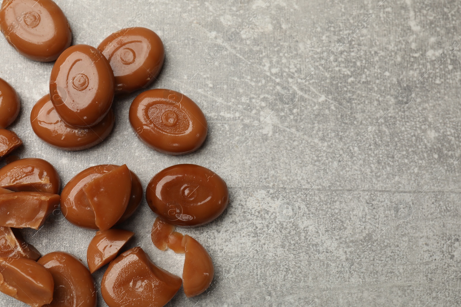 Many tasty caramel candies on grey table, flat lay. Space for text Photo of Many tasty caramel candies on grey table, flat lay. Space for text