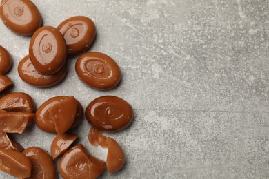 Photo of Many tasty caramel candies on grey table, flat lay. Space for text