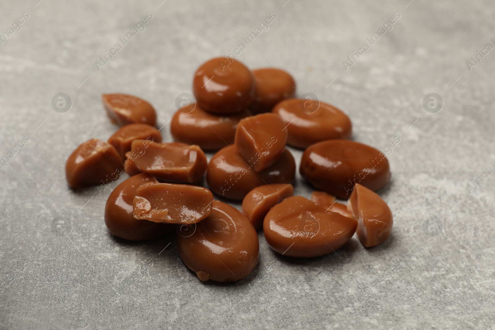 Many tasty caramel candies on grey table, closeup Photo of Many tasty caramel candies on grey table, closeup