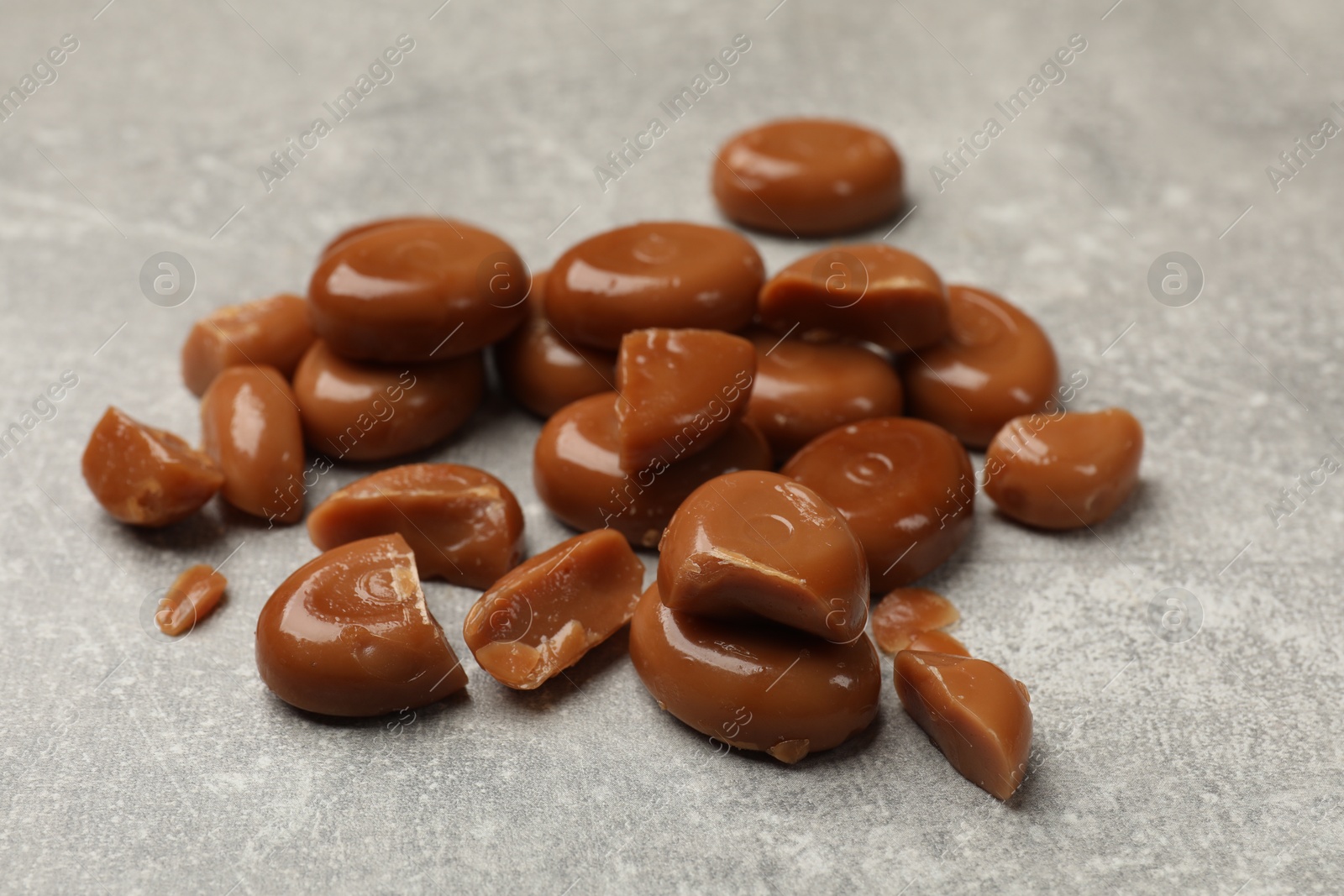 Many tasty caramel candies on grey table, closeup Photo of Many tasty caramel candies on grey table, closeup