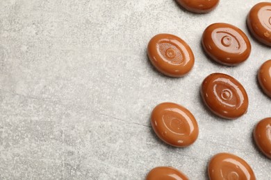 Photo of Many tasty caramel candies on grey table, flat lay. Space for text