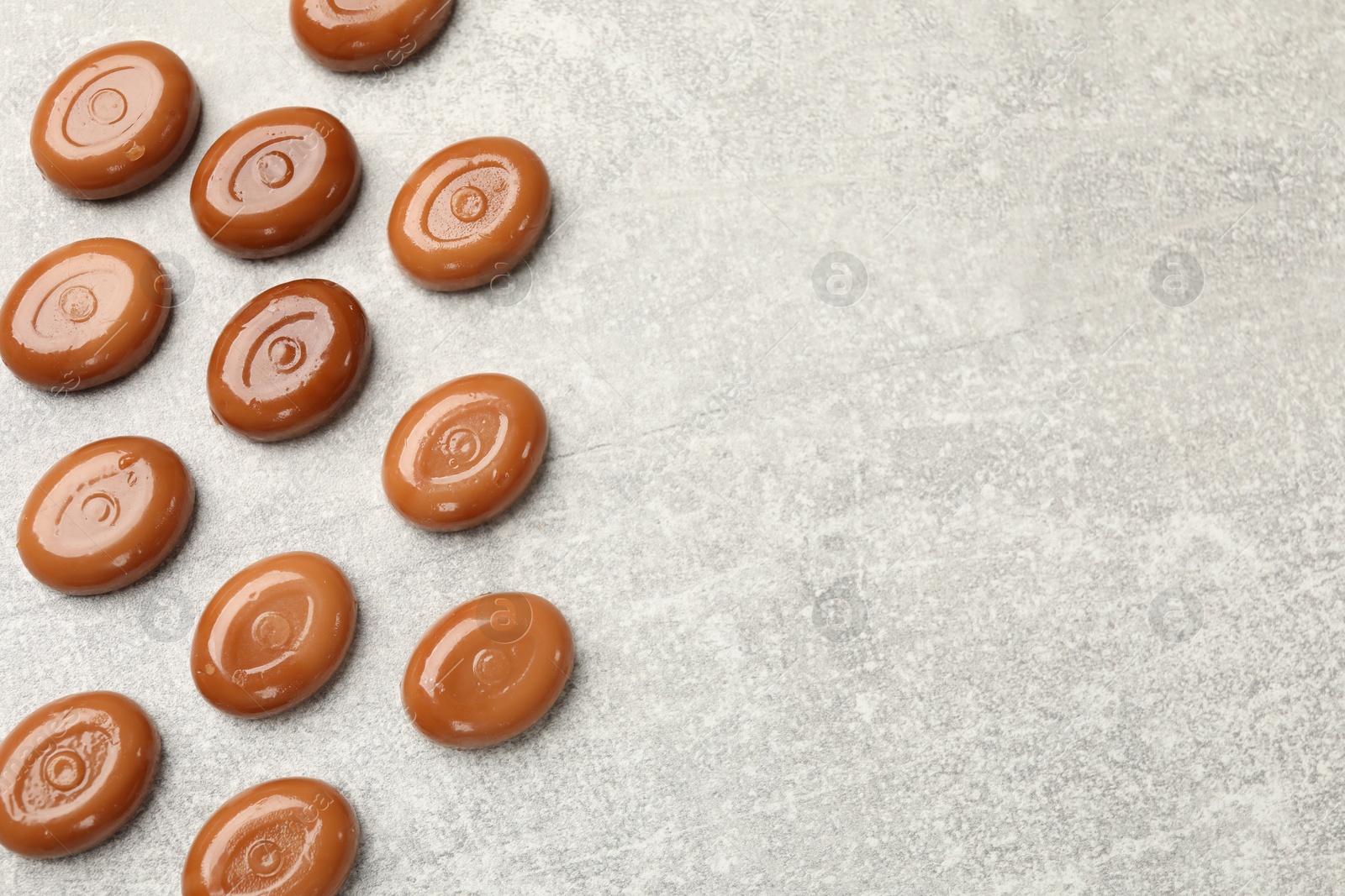Many tasty caramel candies on grey table, flat lay. Space for text Photo of Many tasty caramel candies on grey table, flat lay. Space for text