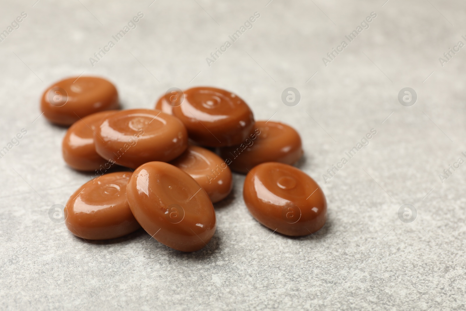 Many tasty caramel candies on grey table, closeup Photo of Many tasty caramel candies on grey table, closeup