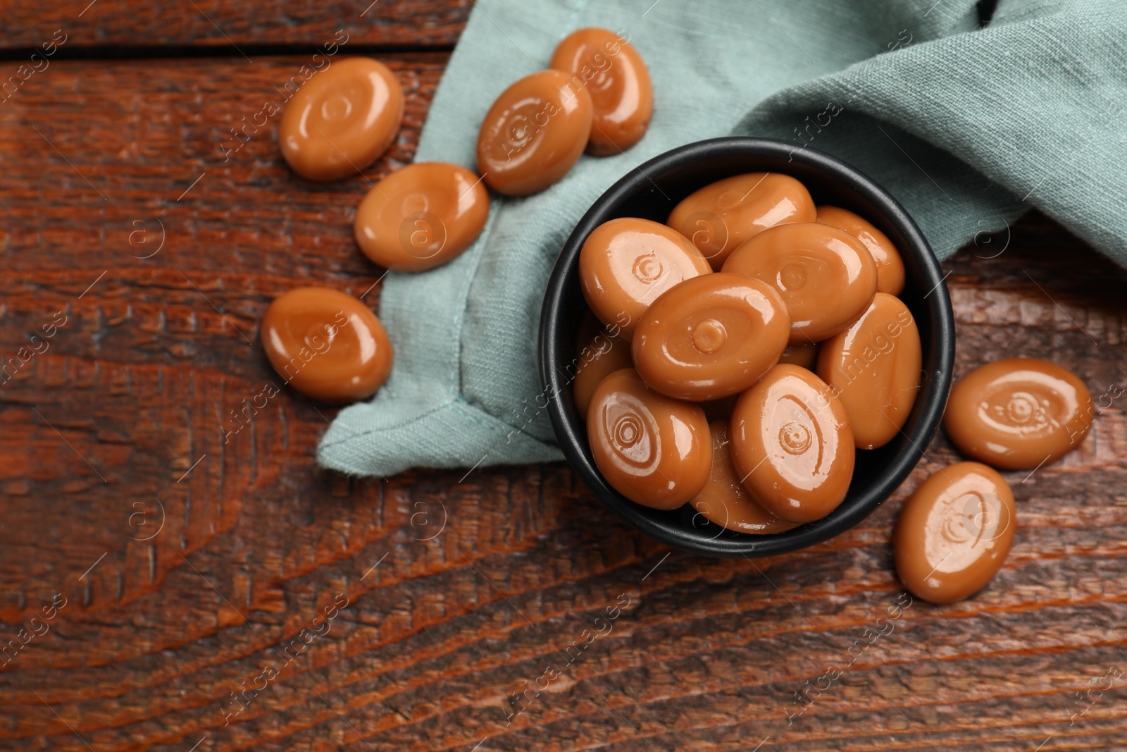 Many tasty caramel candies on wooden table, flat lay Photo of Many tasty caramel candies on wooden table, flat lay