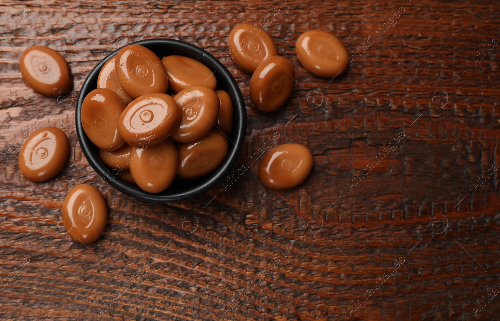 Many tasty caramel candies on wooden table, flat lay. Space for text Photo of Many tasty caramel candies on wooden table, flat lay. Space for text
