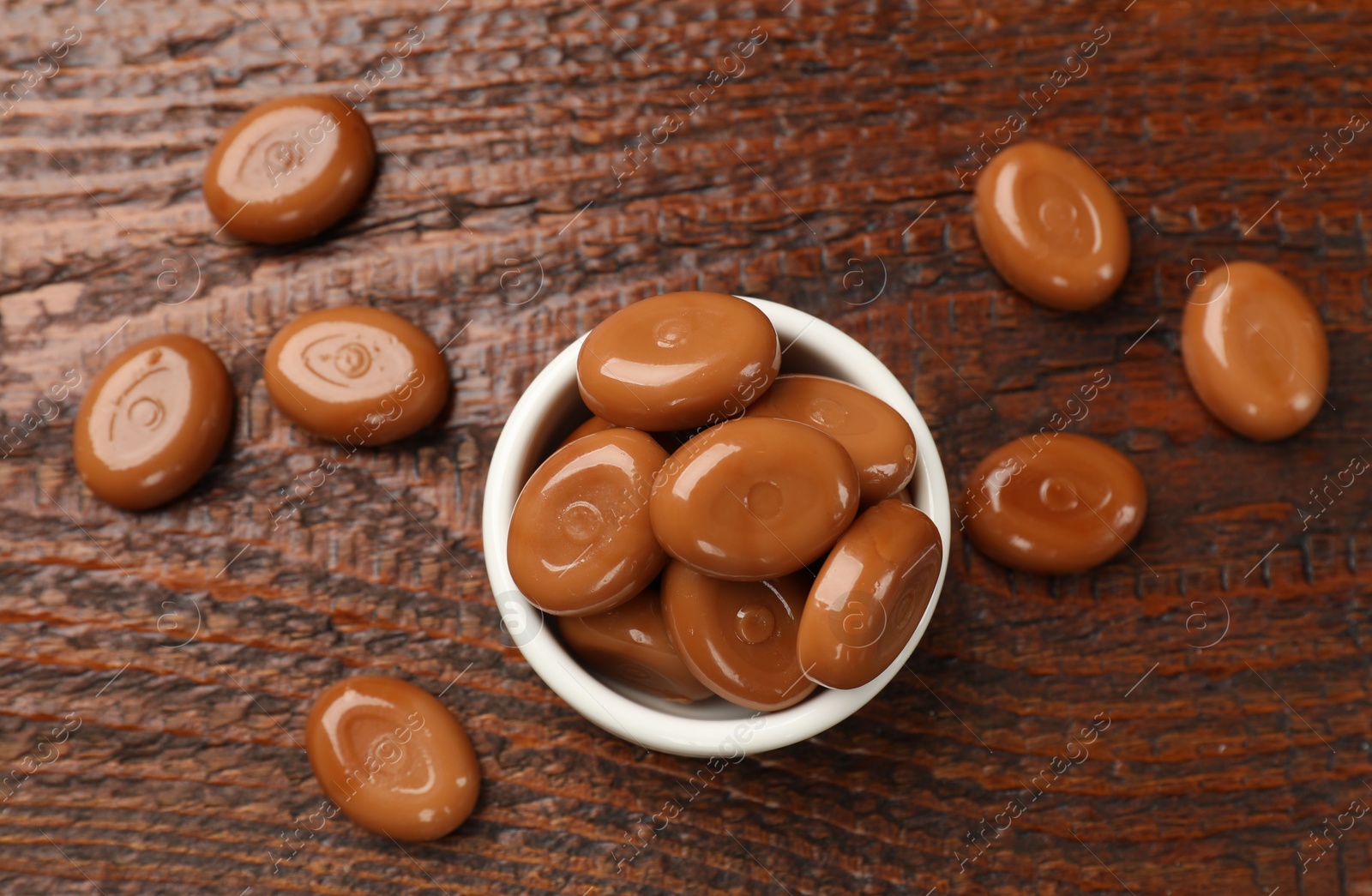 Many tasty caramel candies on wooden table, flat lay Photo of Many tasty caramel candies on wooden table, flat lay