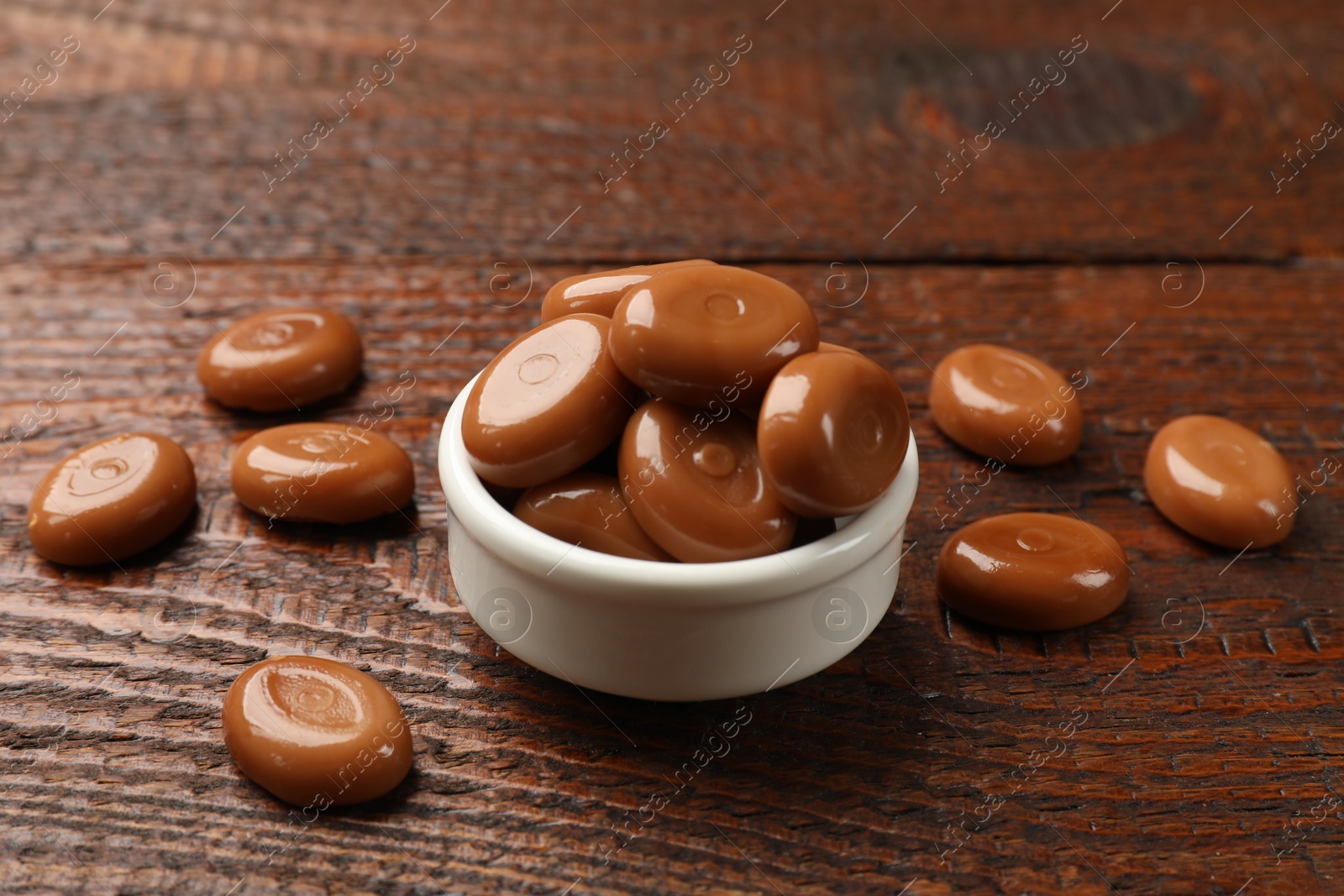Many tasty caramel candies on wooden table, closeup Photo of Many tasty caramel candies on wooden table, closeup