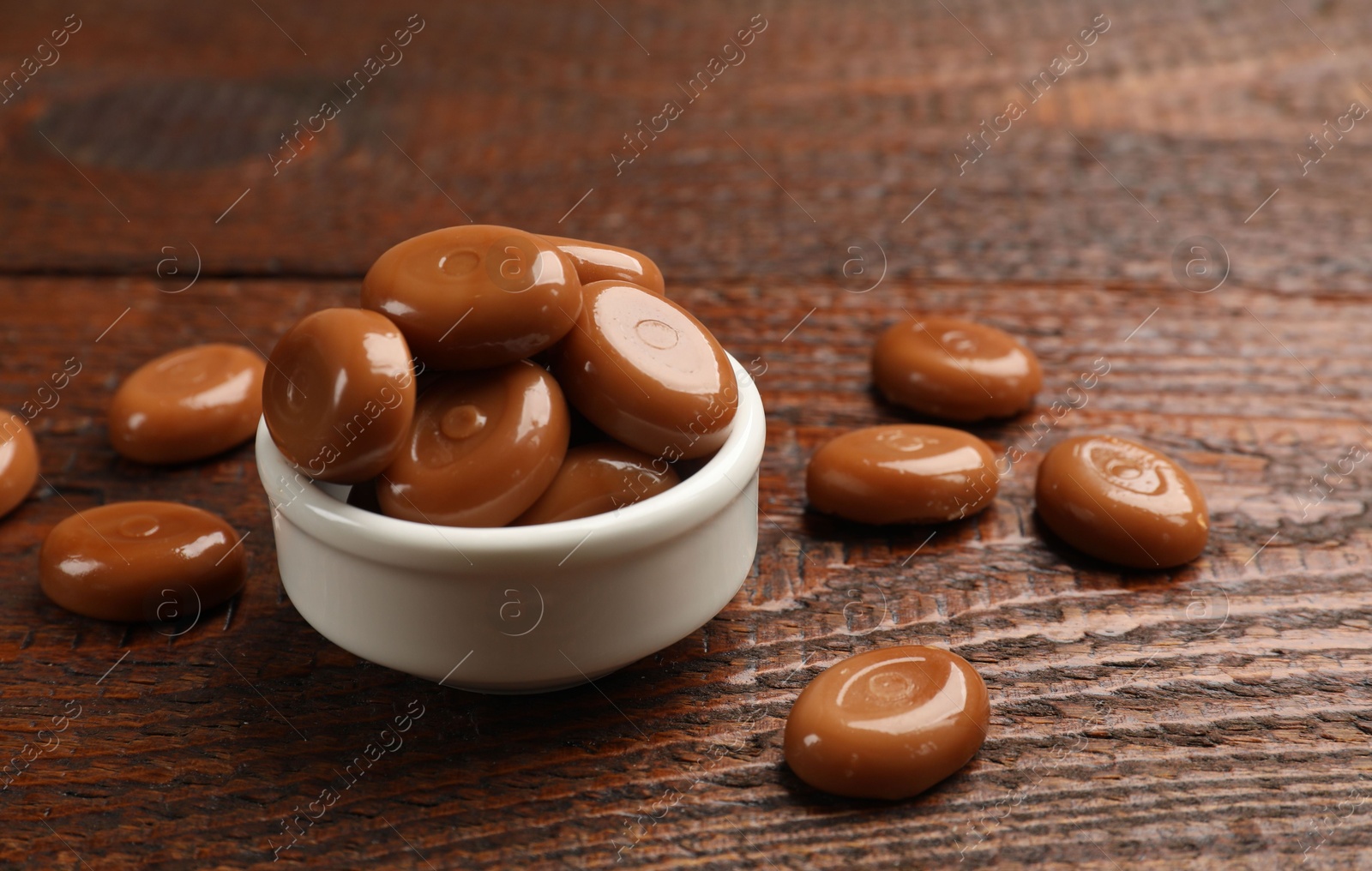 Many tasty caramel candies on wooden table, closeup Photo of Many tasty caramel candies on wooden table, closeup
