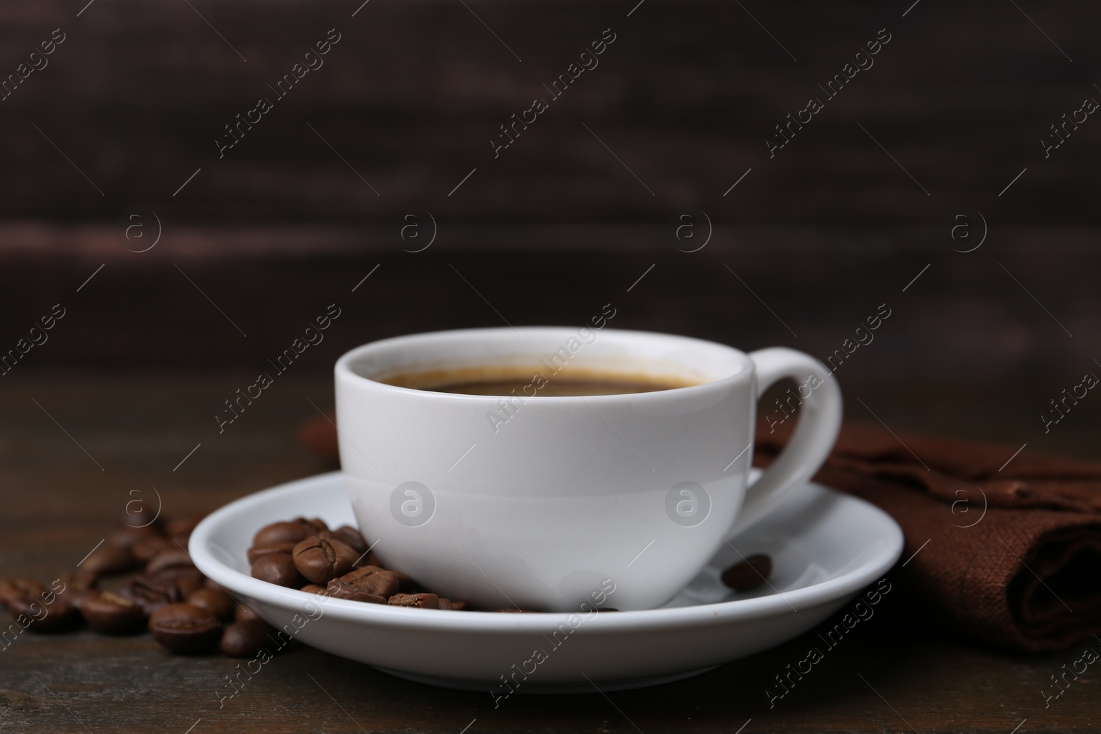 Aromatic coffee in cup, beans and saucer on wooden table, closeup Photo of Aromatic coffee in cup, beans and saucer on wooden table, closeup
