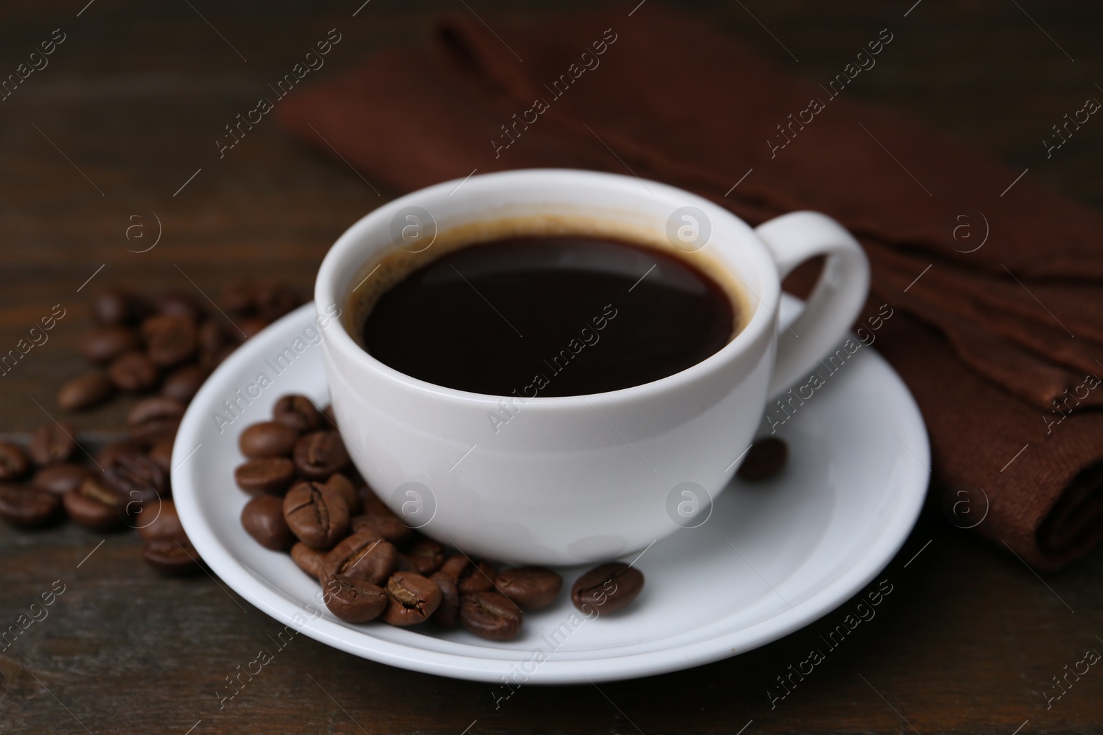 Aromatic coffee in cup, beans and saucer on wooden table, closeup Photo of Aromatic coffee in cup, beans and saucer on wooden table, closeup
