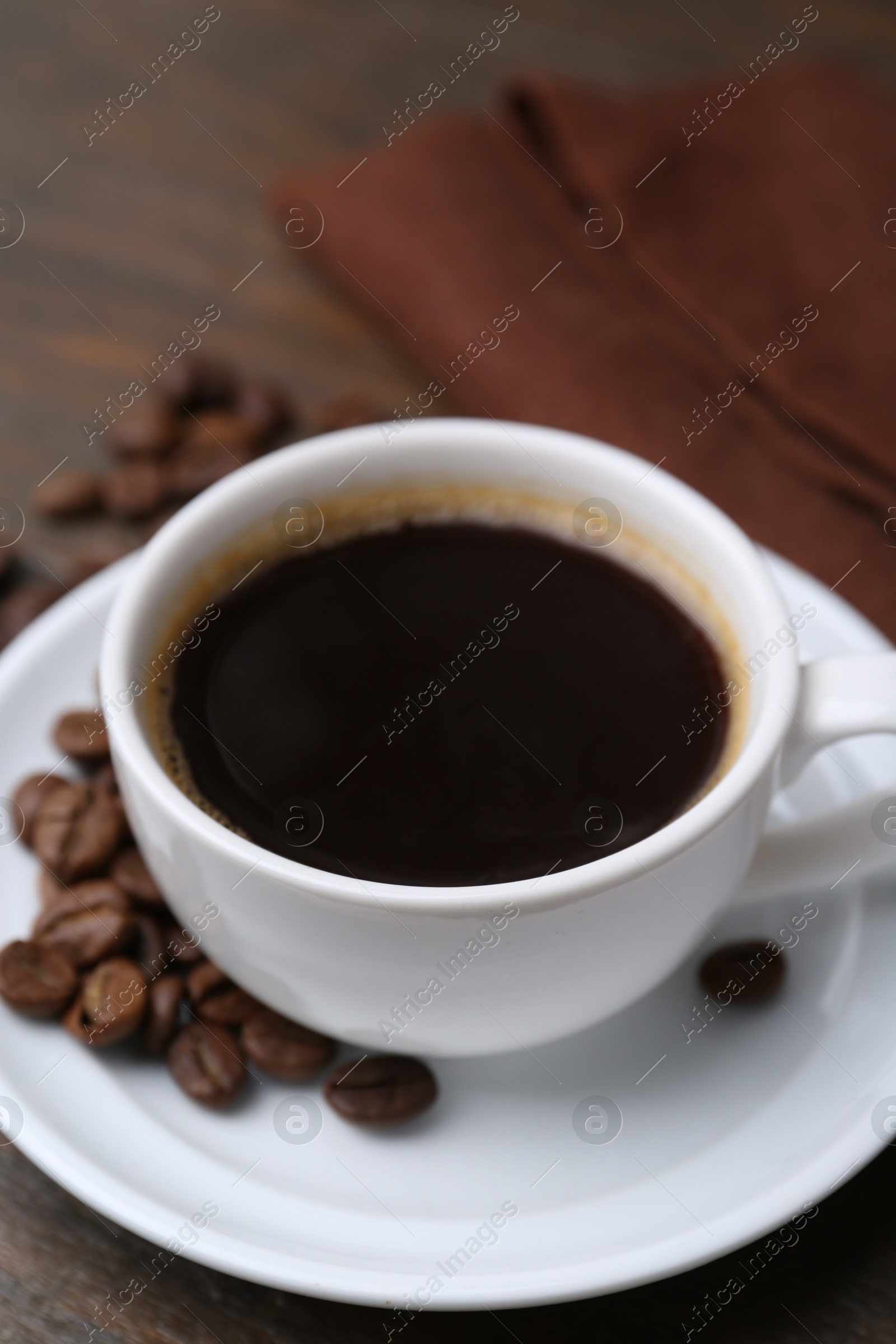 Aromatic coffee in cup, beans and saucer on wooden table, closeup Photo of Aromatic coffee in cup, beans and saucer on wooden table, closeup