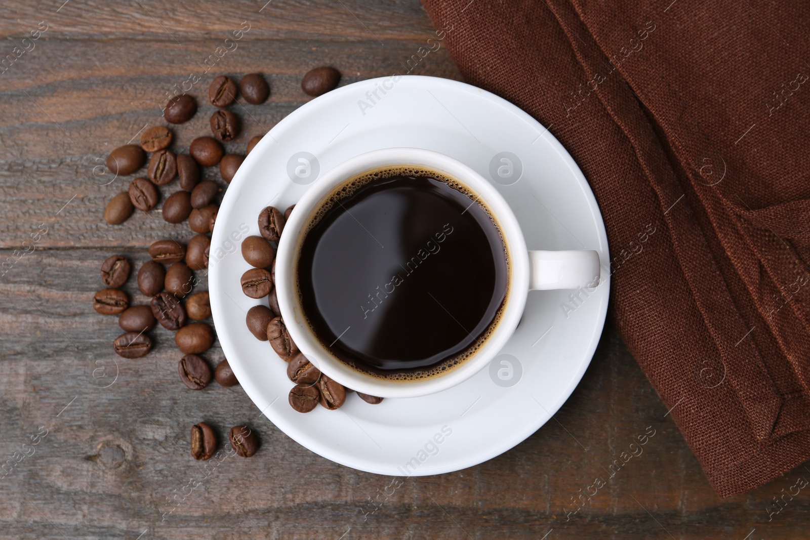 Aromatic coffee in cup, beans and saucer on wooden table, flat lay Photo of Aromatic coffee in cup, beans and saucer on wooden table, flat lay