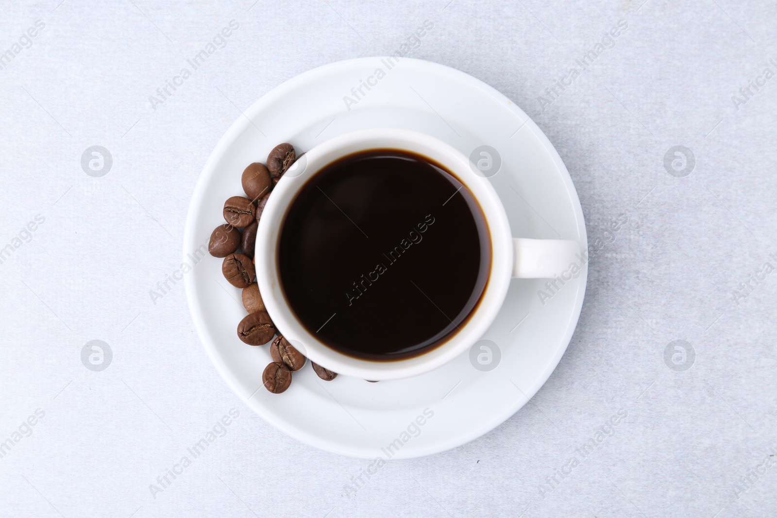 Aromatic coffee in cup, beans and saucer on light table, top view Photo of Aromatic coffee in cup, beans and saucer on light table, top view