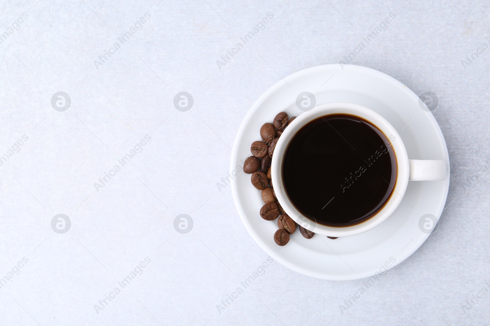 Aromatic coffee in cup, beans and saucer on light table, top view. Space for text Photo of Aromatic coffee in cup, beans and saucer on light table, top view. Space for text