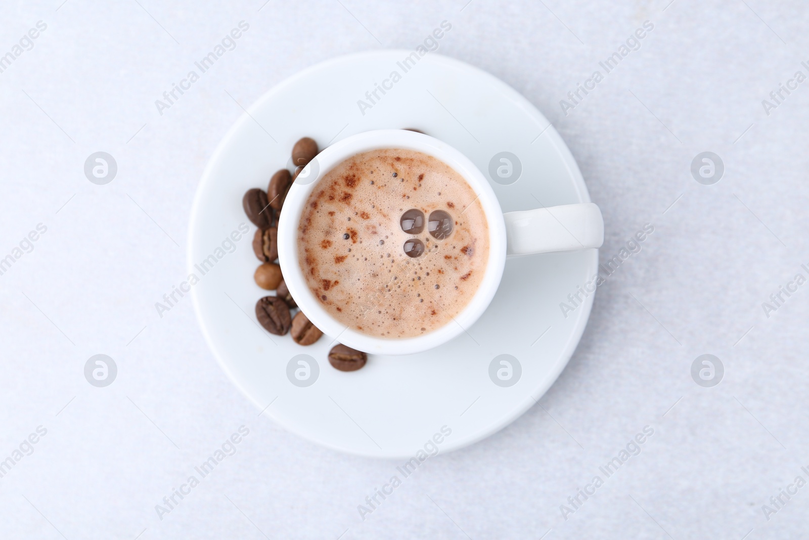 Aromatic coffee in cup, beans and saucer on light table, top view Photo of Aromatic coffee in cup, beans and saucer on light table, top view