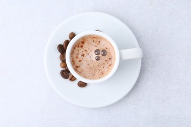 Photo of Aromatic coffee in cup, beans and saucer on light table, top view