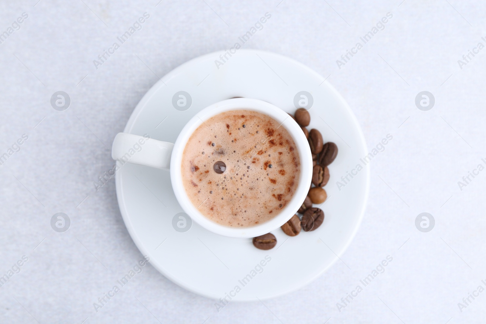 Aromatic coffee in cup, beans and saucer on light table, top view Photo of Aromatic coffee in cup, beans and saucer on light table, top view