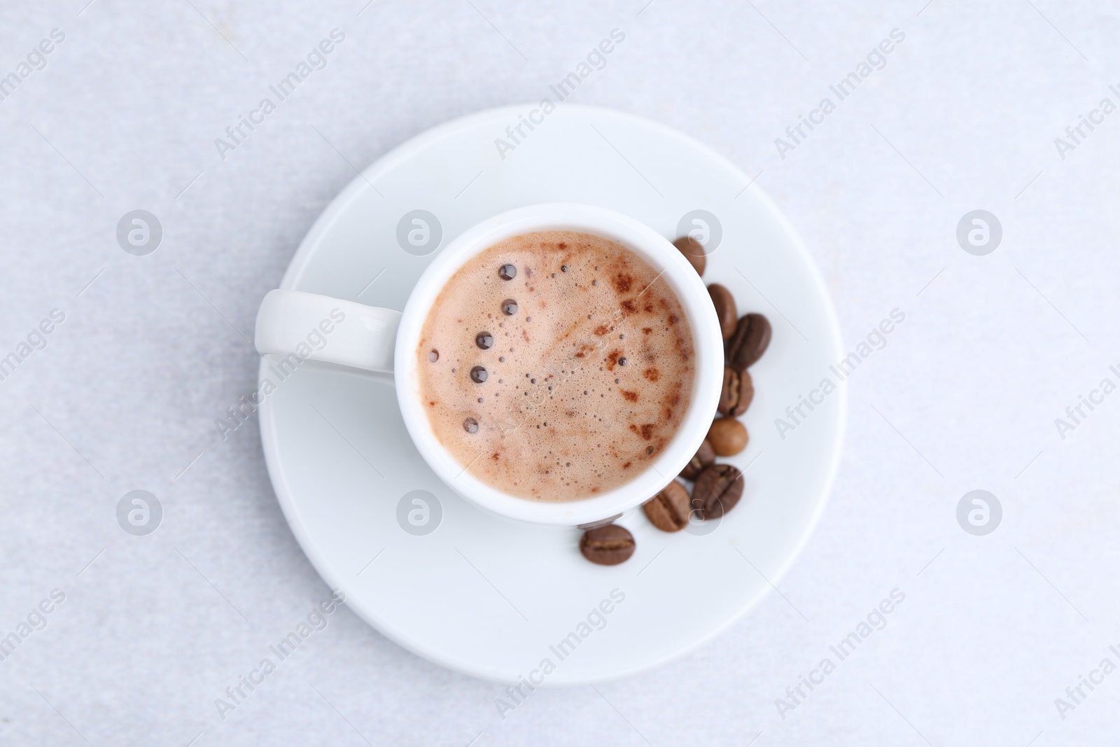 Aromatic coffee in cup, beans and saucer on light table, top view Photo of Aromatic coffee in cup, beans and saucer on light table, top view