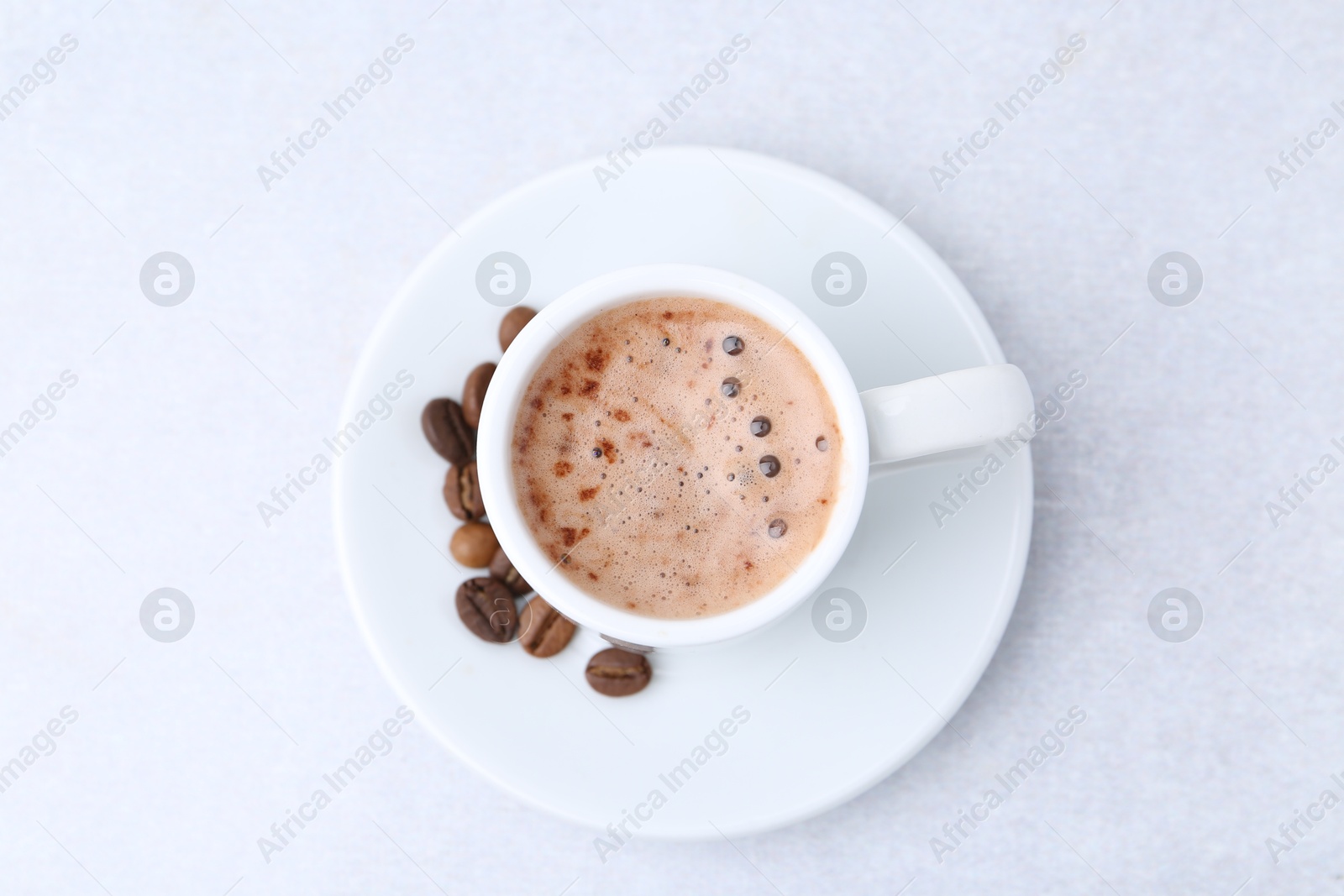 Aromatic coffee in cup, beans and saucer on light table, top view Photo of Aromatic coffee in cup, beans and saucer on light table, top view