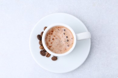 Photo of Aromatic coffee in cup, beans and saucer on light table, top view