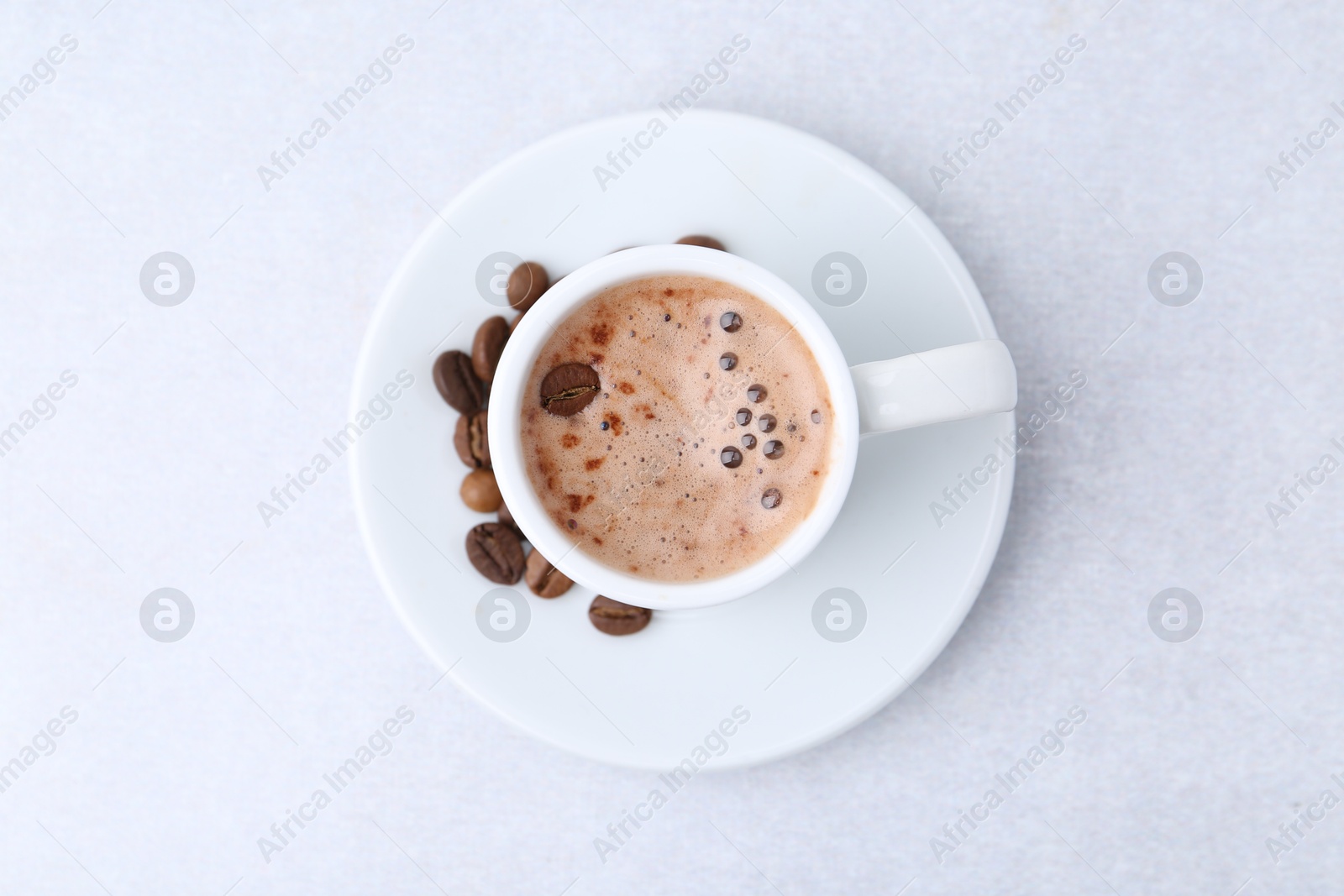 Aromatic coffee in cup, beans and saucer on light table, top view Photo of Aromatic coffee in cup, beans and saucer on light table, top view