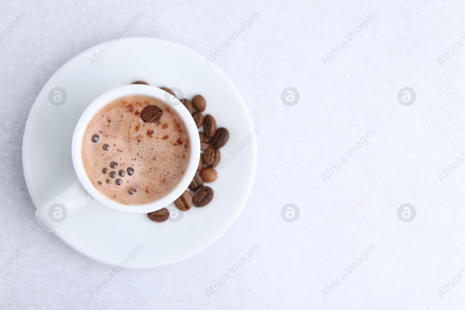 Aromatic coffee in cup, beans and saucer on light table, top view. Space for text Photo of Aromatic coffee in cup, beans and saucer on light table, top view. Space for text
