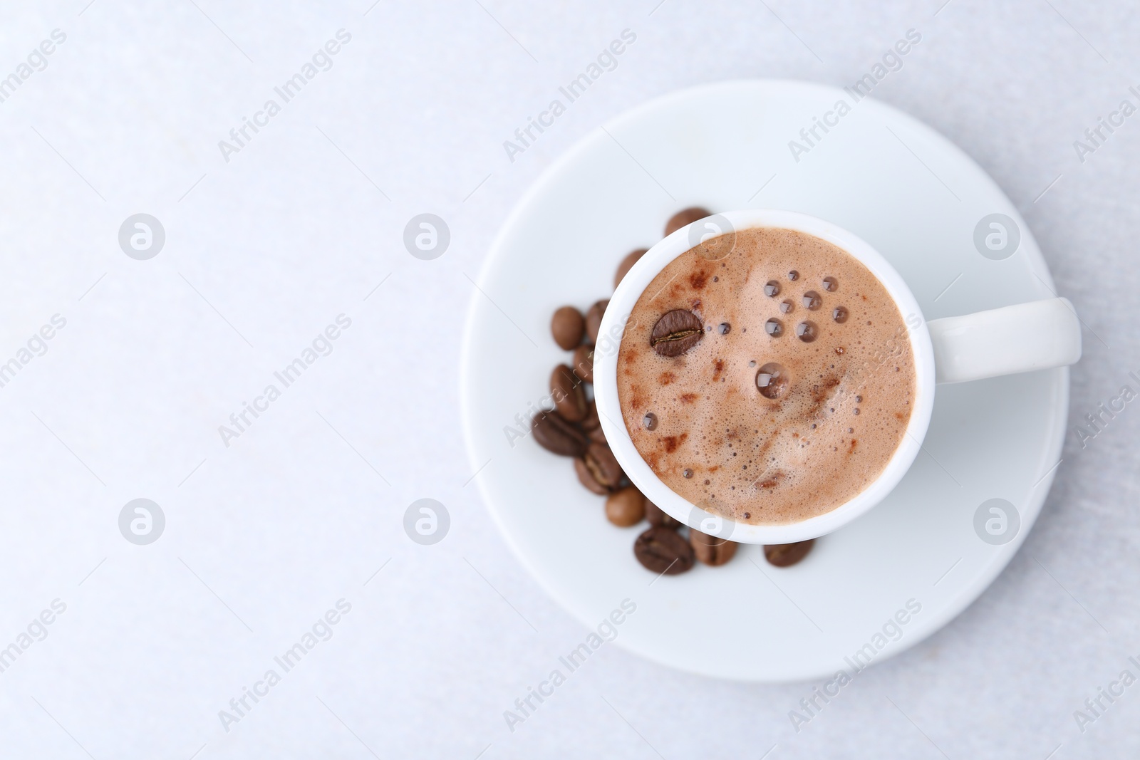 Aromatic coffee in cup, beans and saucer on light table, top view. Space for text Photo of Aromatic coffee in cup, beans and saucer on light table, top view. Space for text