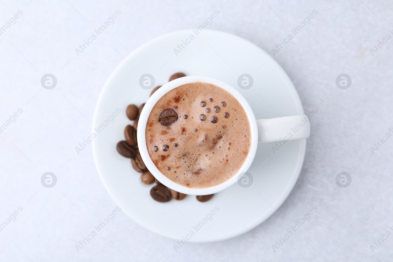 Aromatic coffee in cup, beans and saucer on light table, top view Photo of Aromatic coffee in cup, beans and saucer on light table, top view