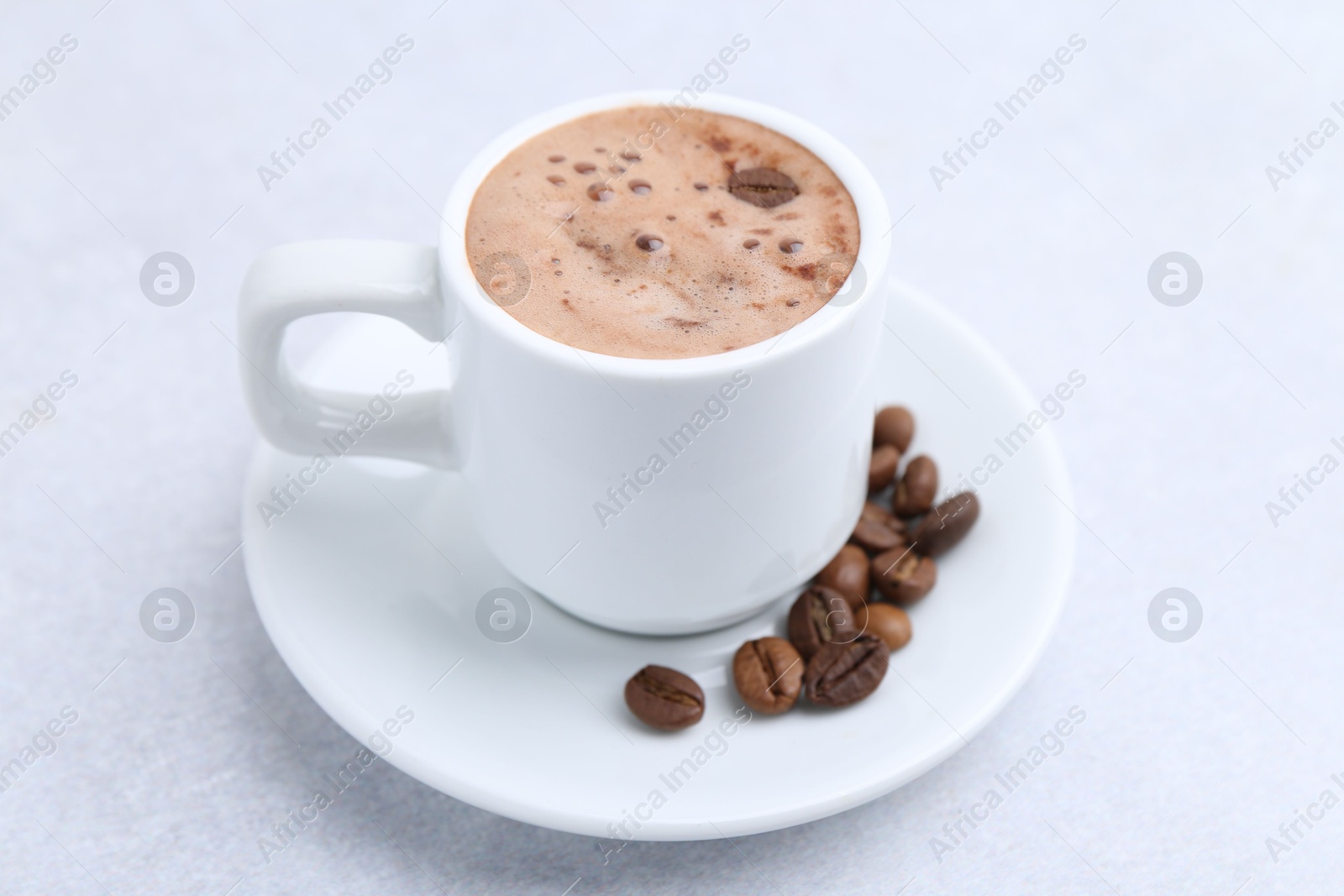 Aromatic coffee in cup, beans and saucer on light table, closeup Photo of Aromatic coffee in cup, beans and saucer on light table, closeup