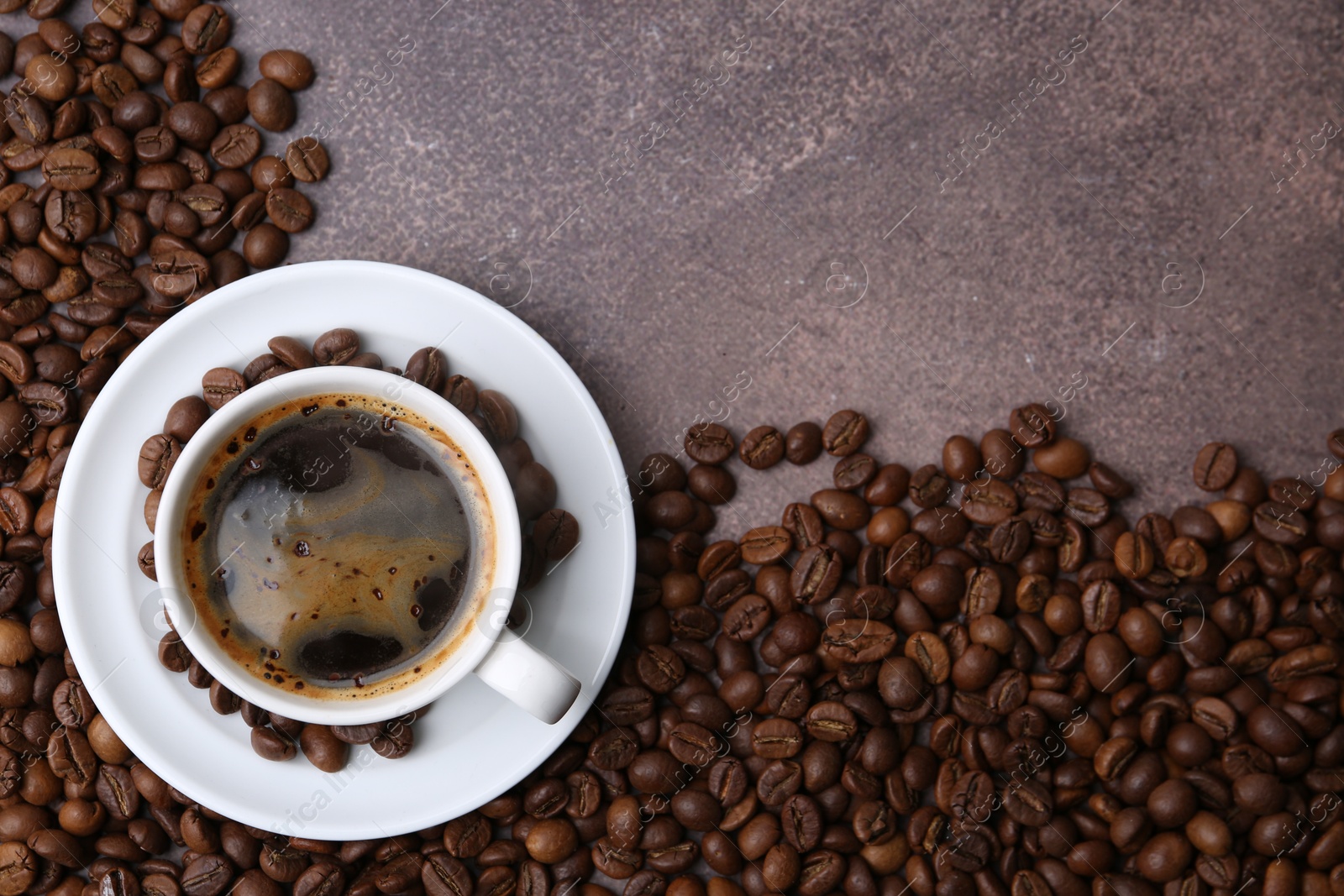 Aromatic coffee in cup, saucer and beans on brown textured table, flat lay. Space for text Photo of Aromatic coffee in cup, saucer and beans on brown textured table, flat lay. Space for text