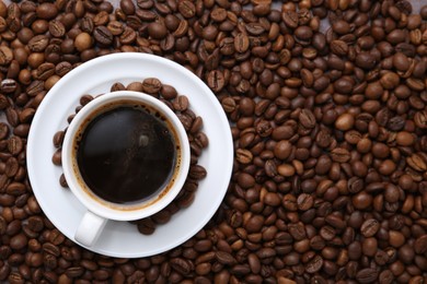 Photo of Aromatic coffee in cup, saucer and beans, top view